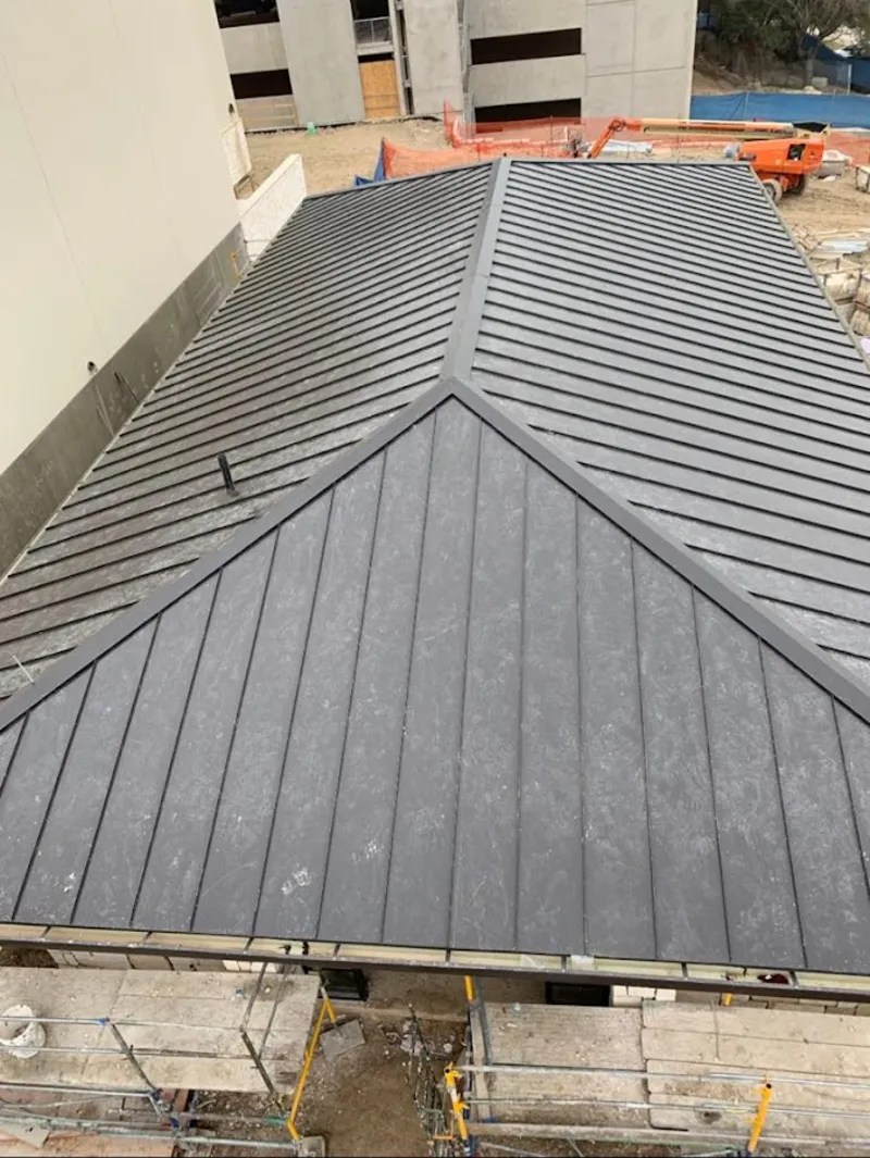 Commercial metal roof construction with crane equipment in Vernon